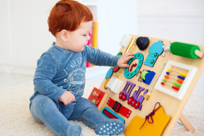 cute toddler baby boy playing with busy board